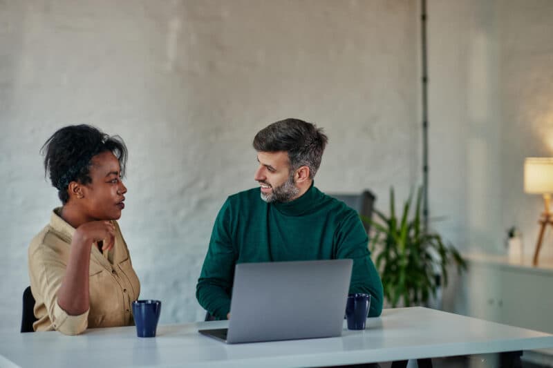 HR professionals discussing work at a desk with a laptop